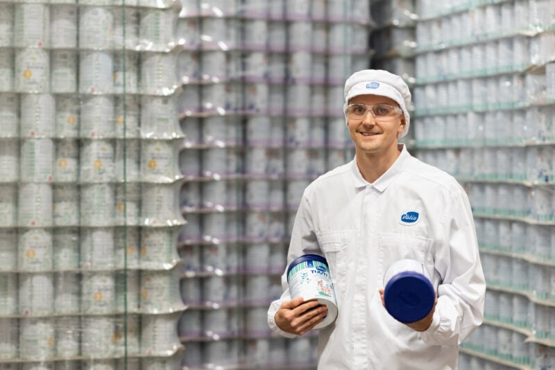 Person standing in the middle of stacks of milk powder cans.